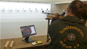 Eine Frau steht mit einem Gewehr im Schießstand