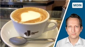 In der linken Bildhälfte sieht man einen servierten Cappuccino. Rechts daneben den Kopf des Autors. 