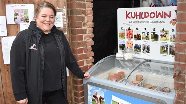 Eine Frau steht neben einer Eistruhe.