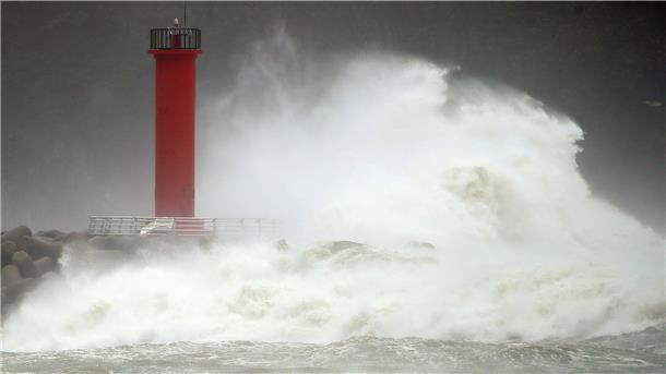 Ein Leuchtturm wird von starken Wellen umspült. 