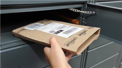 Eine Hand schmeißt ein Paket in einen Briefkasten.