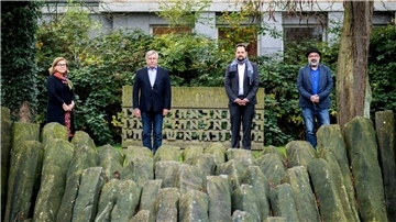 In Oldenburg stehen Politiker neben einem Mahnmal für die Opfer des Nationalsozialismus.