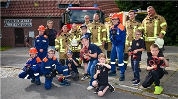 Kinder und Erwachsene vor einem Feuerwehrhaus.