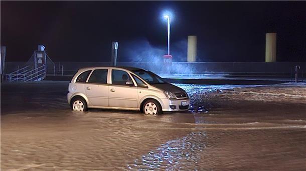 Sturmtief über Deutschland – Bäume stürzen um In Wilhelmshaven steht ein Auto auf einem überfluteten Parkplatz.