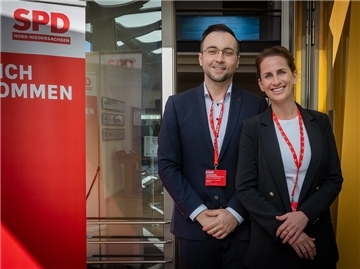 Ein Mann (links) und eine Frau in einem Gebäude, links ist ein roter Banner zu sehen und die weißen Buchstaben SPD. Ina Helwig und Sebastian Brandt: Die SPD im Kreis Rotenburg setzt nach eigenen Angaben auf Bürgernähe und Sachpolitik.