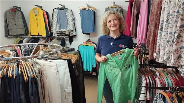 Eine Frau hält ein Kleidungsstück in der Hand. Sie steht in einem Bekleidungsgeschäft.