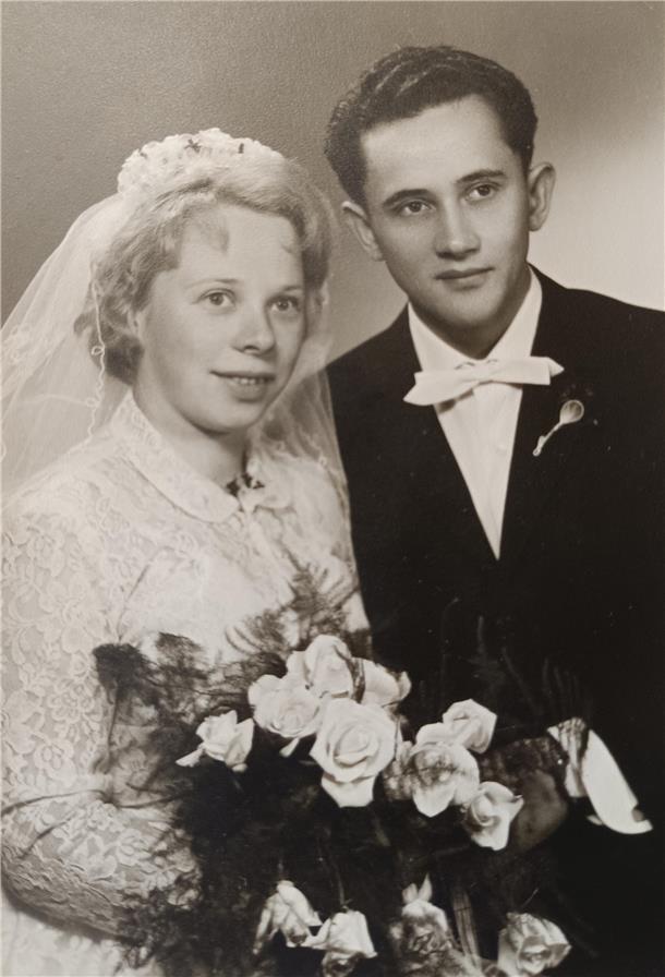 Eine Frau im weißen Hochzeitskleid und ein Mann im Anzug mit weißer Fliege.