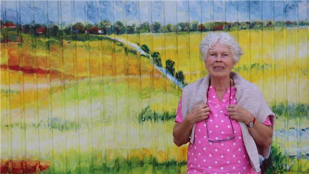 Garagenkunst in Butjadingen zu sehen Inge van de Felde vor dem Tor Nr. 5 mit dem Bild „Düker Groden“ .