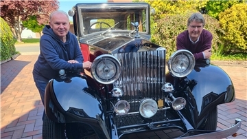 Zwei Männer lehnen sich an einem Oldtimer an. 