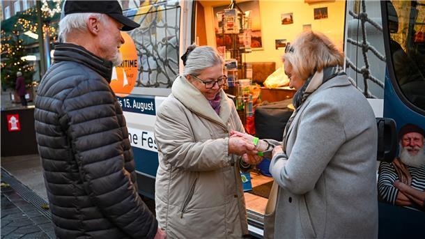 2G auf dem Weihnachtsmarkt: Wie wird kontrolliert? Ingrid Gottschalk (Mitte) verteilt nach Kontrolle des Impfnachweises die Armbänder an die Bremerhavener Christa und Jörg Fischoeder.