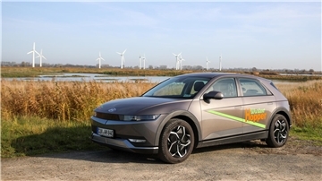 Hyundai Ioniq 5 steht vor Schilffeldern und einem Windpark im Hintergrund
