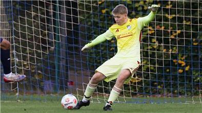 Ein Mann schießt einen Ball auf ein Tor. Der Torwart hält den Ball.