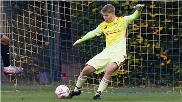 Ein Mann schießt einen Ball auf ein Tor. Der Torwart hält den Ball.