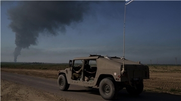 Israelische Soldaten in der Nähe der Grenze zwischen Israel und dem Gazastreifen, während in dem Küstengebiet Rauch in den Himmel steigt.