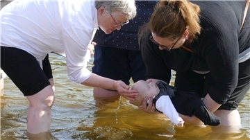 Ist es Tom oder ist es Theo? Jedenfalls einer der beiden Zwillinge wird von der Taufpatin (rechts) in Händen gehalten, während Pastorin Christa Maschke ihn mit Seewasser beträufelt.