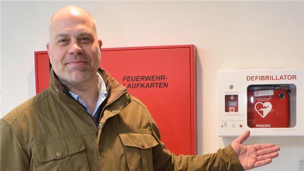 Mann zeigt auf Kasten mit Defibrillator