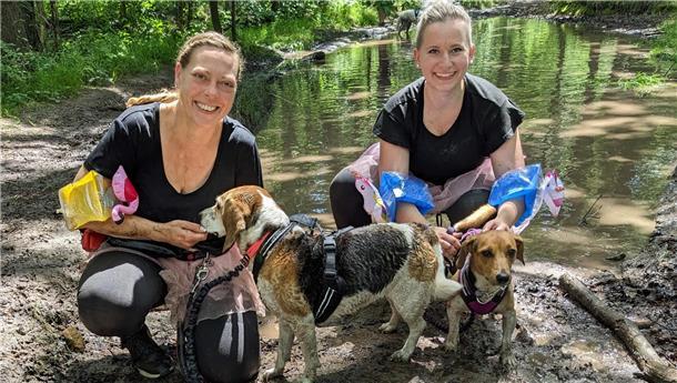 Letzte Runde in Hoope? Hunderte Menschen und Hunde toben durch den Sportpark Zwei Frauen mit Schwimmflügeln und rosa Tutus knien mit ihren Hunden vor einem kleinen Teich