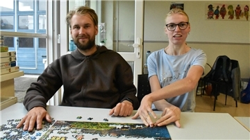 Ein junger Mann und eine junge Frau sitzen an einem Tisch.