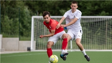 Zwei Männer in Sporttrikots kämpfen um einen Ball.