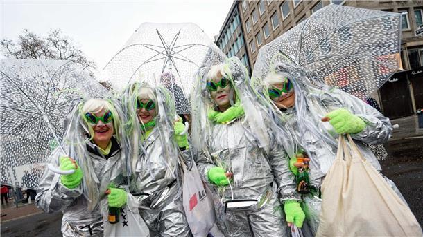 Jecken schützen sich beim traditionellem Kö-Treiben auf der Düsseldorfer Königsallee mit Schirmen vor dem Regen.