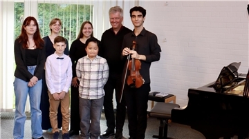 Eine Gruppe von jungen Musikern stellt sich zu einem Foto vor einem Klavier auf.