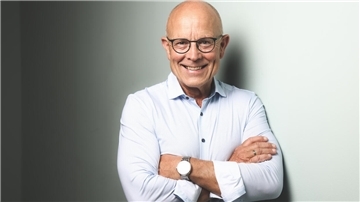 Porträt eines Mannes mit einem weißen Hemd, Glatze und Brille.