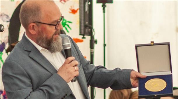 Jörn Leiding vom Kreissportbund überbringt eine Plakette des Landessportbundes zum Jubiläum des TSV Rhade.