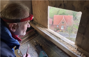 Johannes Bartner hat ein Quadrat in das Holz der Glockenluke gesägt, in das exakt der Nistkasten passt. Bevor er ihn einsetzt, genießt er den spektakulären Blick über Burhave.