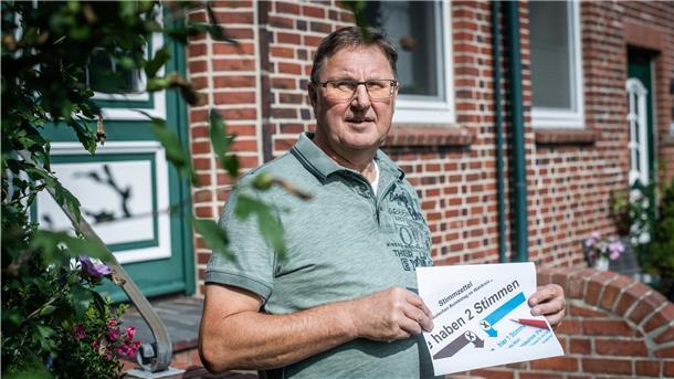 Ein Mann hält einen Wahlzettel in der Hand.
