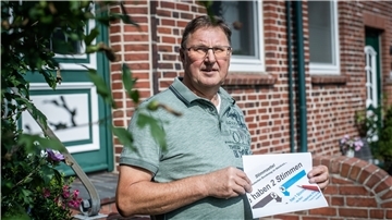 Ein Mann hält einen Wahlzettel in der Hand.