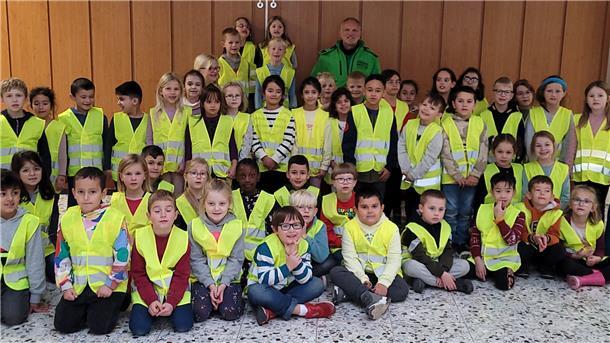Jürgen Zimmer von der Verkehrswacht Nordenham freut sich mit den Erstklässlerinnen und Erstklässlern der Südschule über die Warnwesten.