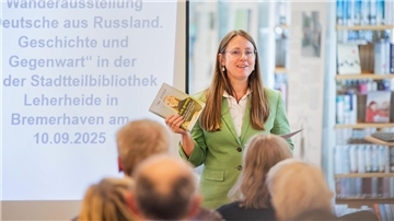 Eine Frau spricht vor Menschen in einer Bibliothek. 