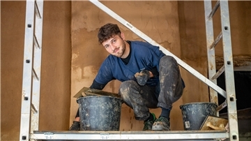 Julian aus Frankreich verputzt auf der Baustelle des WERK-Hauses zum ersten Mal Lehm.