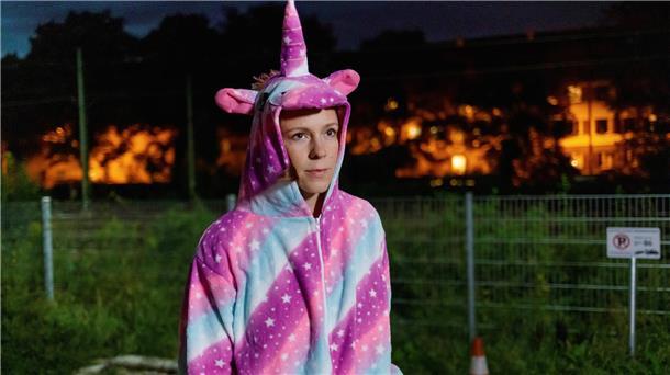 Frau in Einhorn-Kostüm geht draußen spazieren.