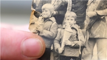 Kai Oppermann, in DDR-Kinderheimen groß geworden, zeigt ein Foto von seiner Einschulung. In der Bildmitte ist er in der vorderen Reihe mit Zuckertüte zu sehen. Links daneben steht sein Bruder Patrick.