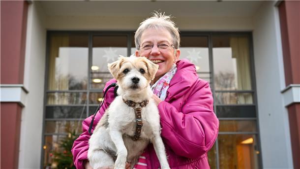 Frau mit Hund vor einem Haus