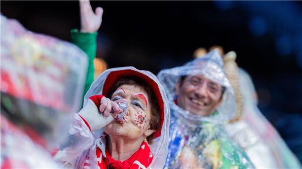 Karnevalisten mit Regenschutz feiern an Weiberfastnacht die Eröffnung des Straßenkarnevals auf dem Alter Markt in Köln.