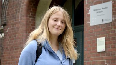Die Schülerin Kathrin Berger steht vor dem Portal der Wilhelm-Raabe-Schule.