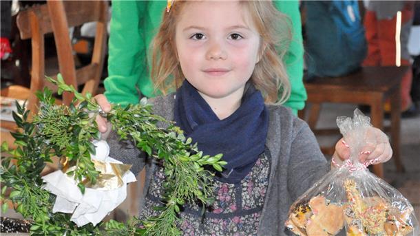 Einladung zu Weihnachtsfeier im LandPark Lauenbrück Ein Mädchen hält einen selbst gebastelten Kranz und selbst gebackene Kekse in den Händen