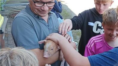 KGS-Schüler streicheln ein Ferkel auf dem Hof von Landwirt Ralf Wülpern in Rockstedt.