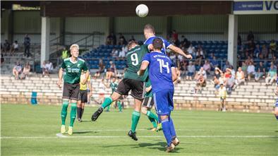 Sechs Männer stehen in Trikots auf dem Fußballplatz.