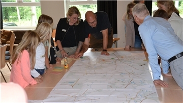 Kinder und Erwachsene beugen sich über einen Stadtplan von Zeven