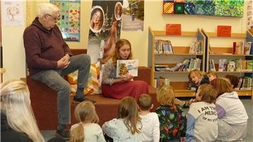 Autorin Lina Maria Bullwinkel liest in einer Leseecke der Gemeindebücherei Loxstedt aus ihrem Buch "Ellie & der Bär" vor. Kinder und Erwachsene hören aufmerksam zu.