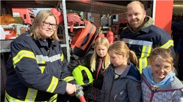  Kinderfeuerwehrwartin Tina Bock-Horning und ihr Stellvertreter Sören Marten zeigen den Kindern die Ausrüstung der Feuerwehr.  