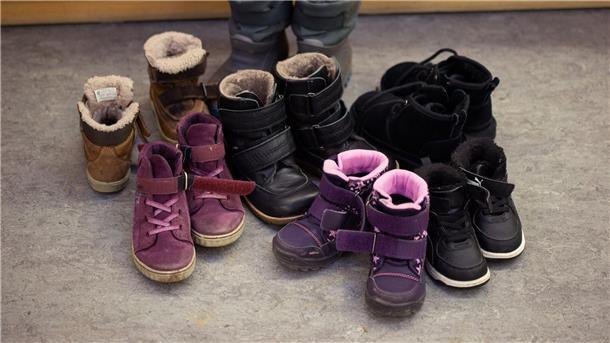 Kinderschuhe und -stiefel sind auf dem Boden in einer Kindertagesstätte abgestellt.