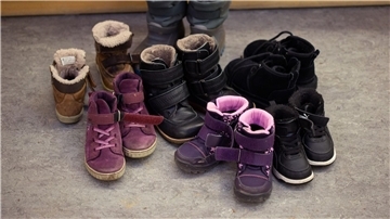 Kinderschuhe und -stiefel sind auf dem Boden in einer Kindertagesstätte abgestellt.