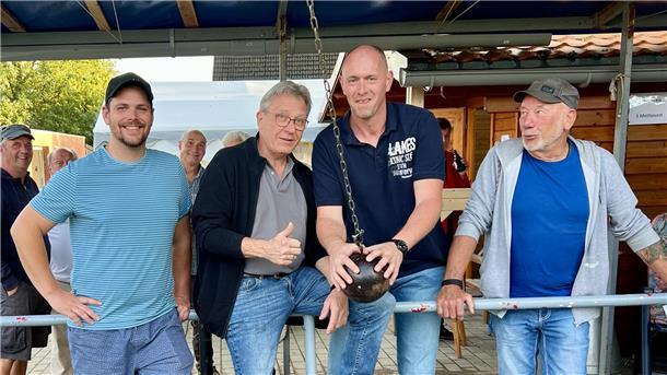 Vier Männer stehen an einer Absperrung.