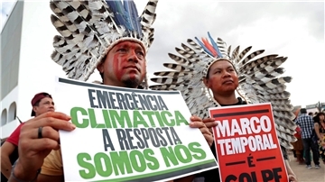 „Klima-Notstand - die Antwort sind wir“ steht auf dem Plakat (r) eines indigenen Demonstranten, der in Brasilia gegen den Gesetzesentwurf zur Ausweisung von Schutzgebieten protestiert.