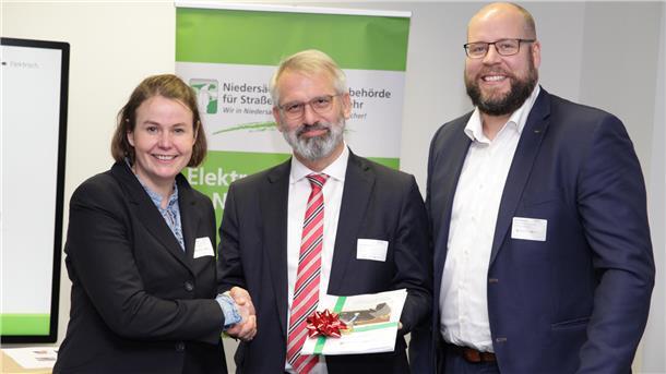 E-Mobilität: Landkreis schließt Ausbaustrategie ab – Konzeptübergabe in Hannover Klimaschutzmanagerin Dr. Meike Düspohl (links) und Patrick Monsees von der Wirtschaftsförderung (rechts) erhalten von Timo Quander, dem Präsidenten der Landesbehörde (NLStBV), das Ladeinfrastrukturkonzept für den Landkreis Rotenburg.