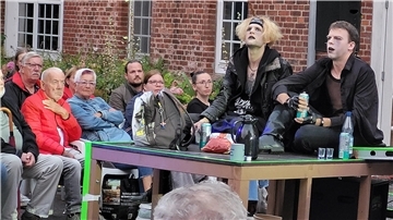 Bild von zwei Schauspielern und Publikum bei der Premiere des Stücks "Krabat" an der Moorseer Mühle